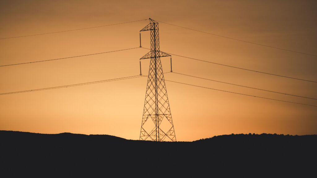 Silhouette of a transmission tower against a vibrant sunset in Jendouba, Tunisia.